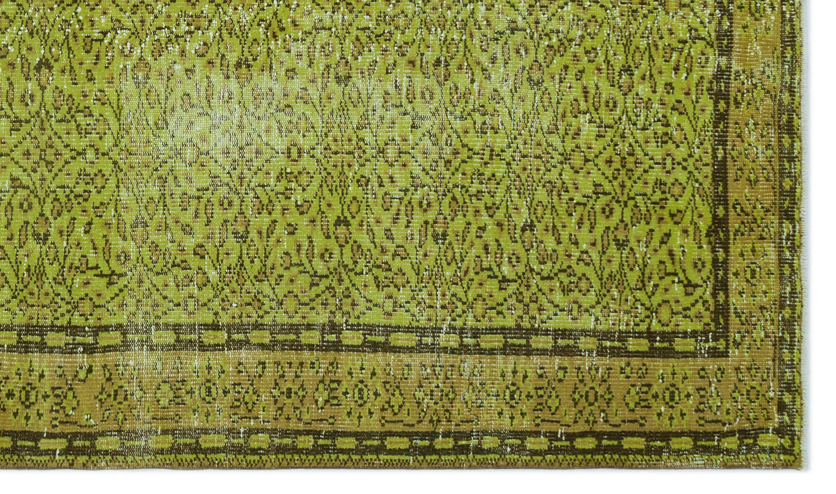 Chartreuse and brown vintage-style rug with a distressed floral pattern and a geometric border.