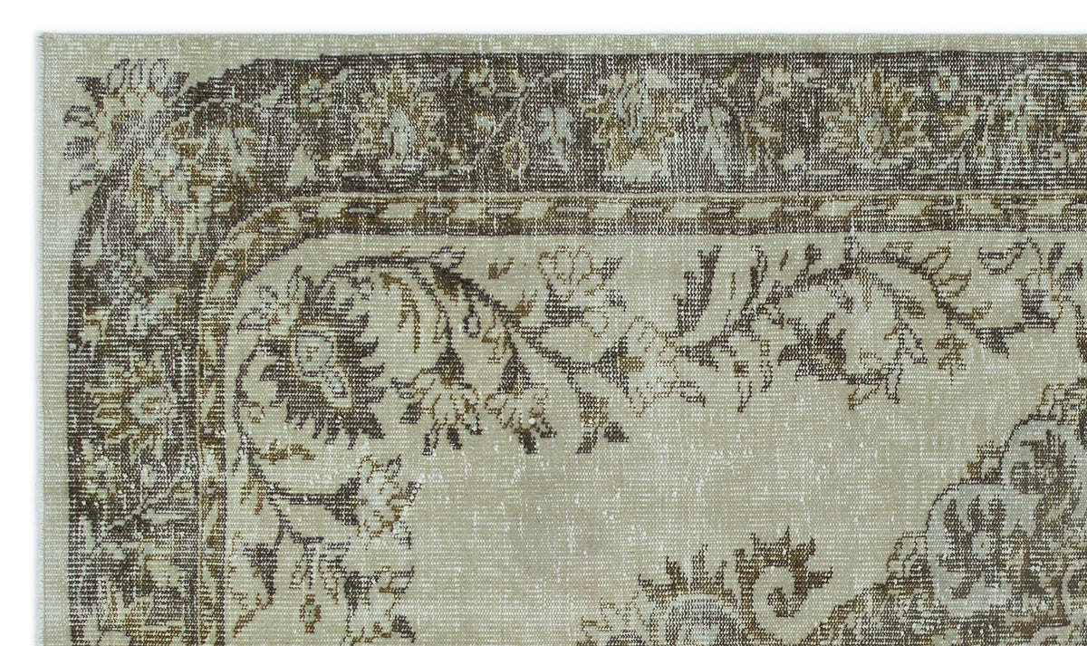 Beige and brown distressed rug with a traditional floral border and central medallion pattern.