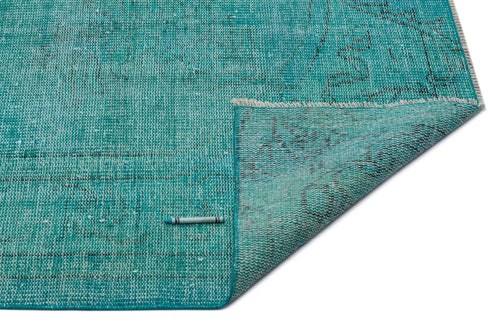Load image 1 in gallery view. Teal distressed rug with a faded traditional pattern, shown with a corner folded over on a white background.