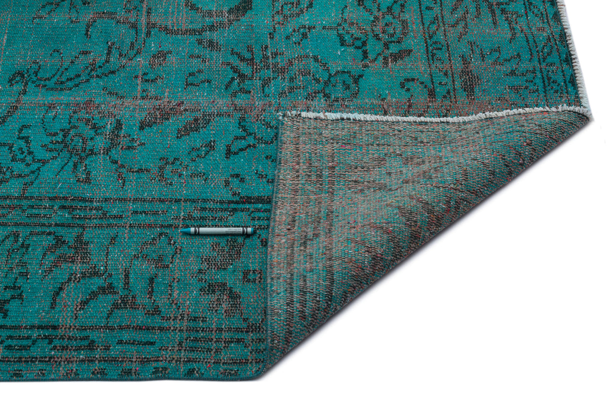 Teal and black distressed traditional rug with a folded corner revealing the textured backing on a white background.
