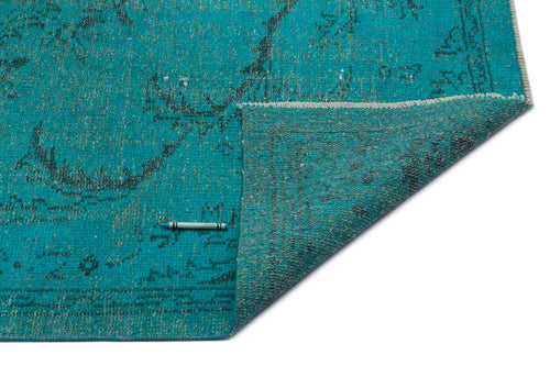 Load image 1 in gallery view. Teal distressed rug with a faded floral pattern, shown with a corner folded over on a white background.