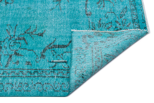 Load image 1 in gallery view. Turquoise distressed rug with a dark grey floral pattern and a folded corner showing the underside.