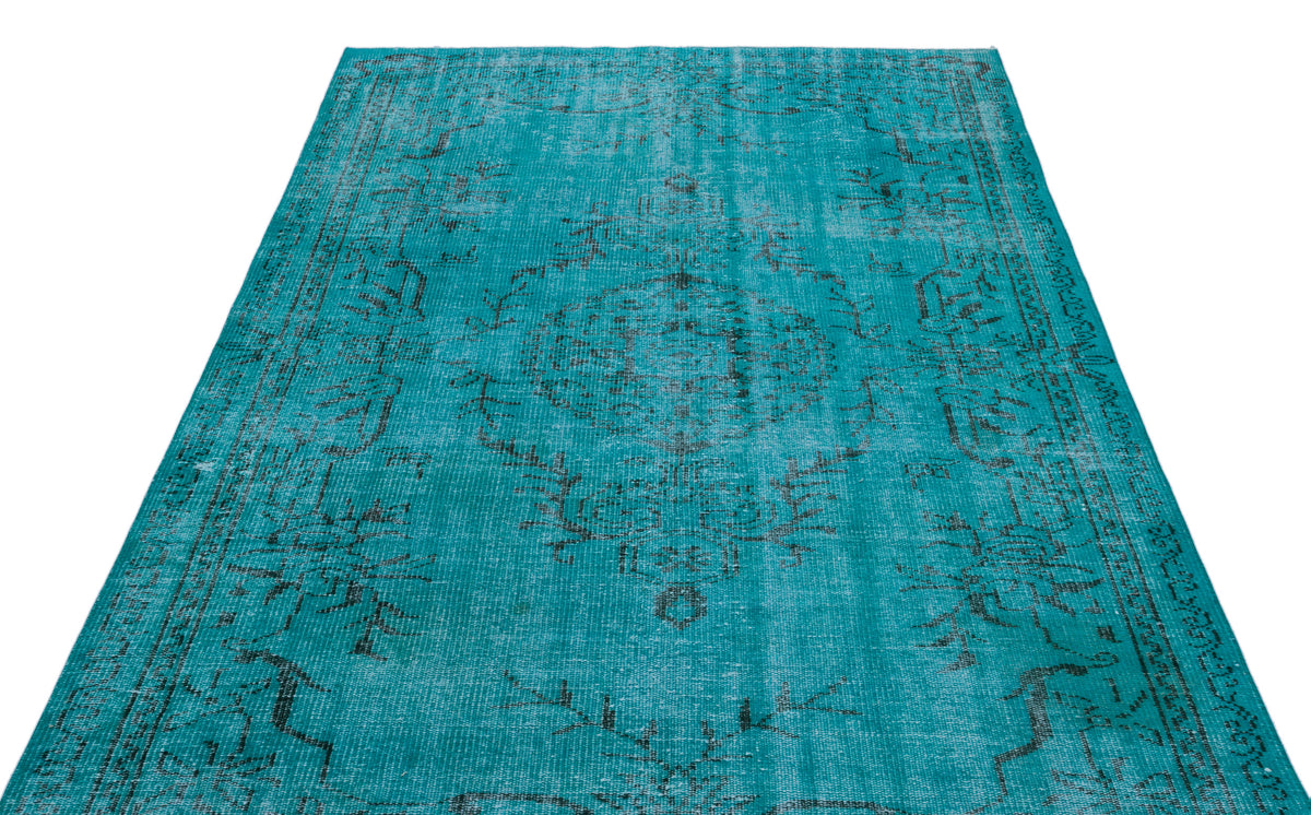 Distressed turquoise rug with a dark grey traditional floral medallion pattern on a white background.