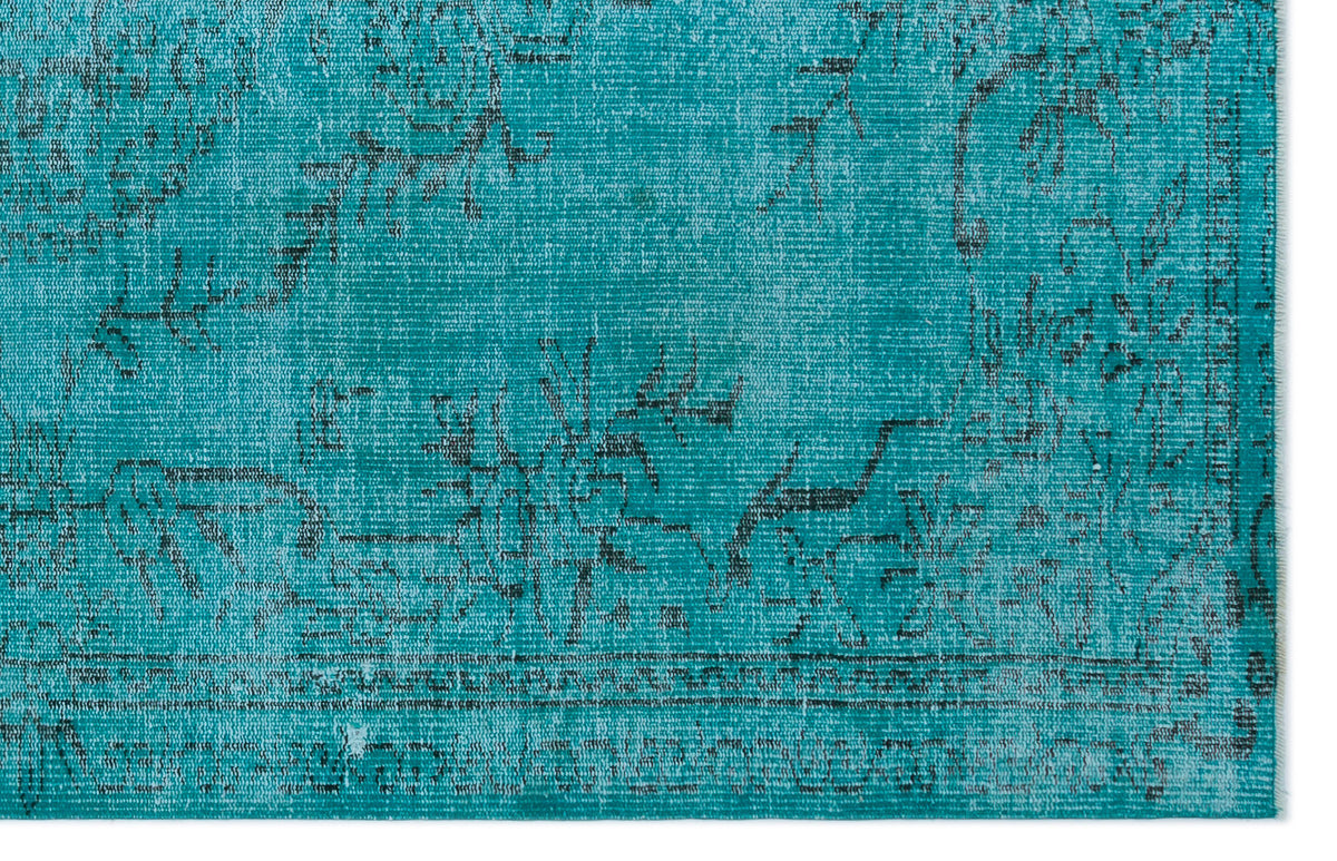 Teal rug with a distressed black traditional floral medallion pattern and a bordered edge.