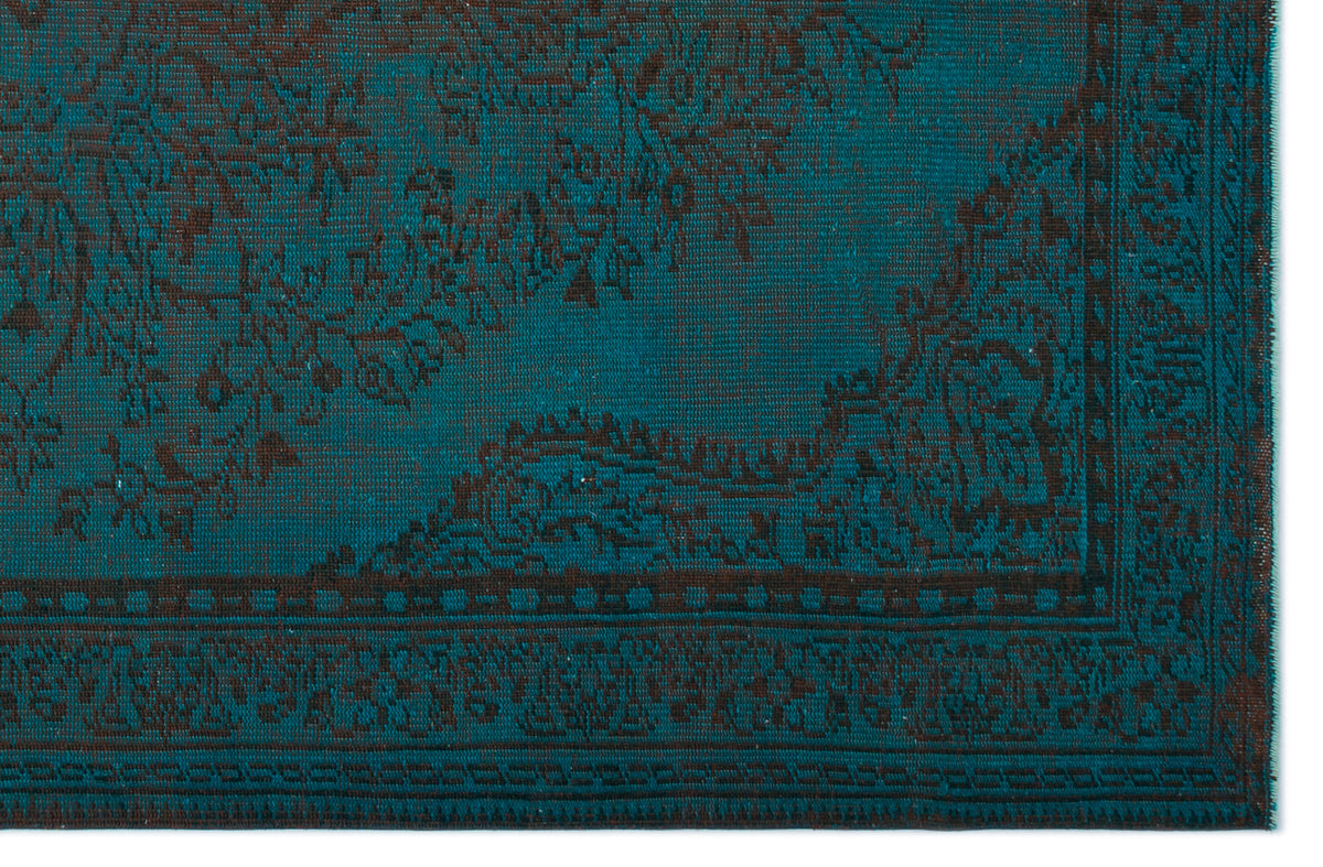 Teal and dark brown rug with a traditional distressed floral medallion pattern and a geometric border.