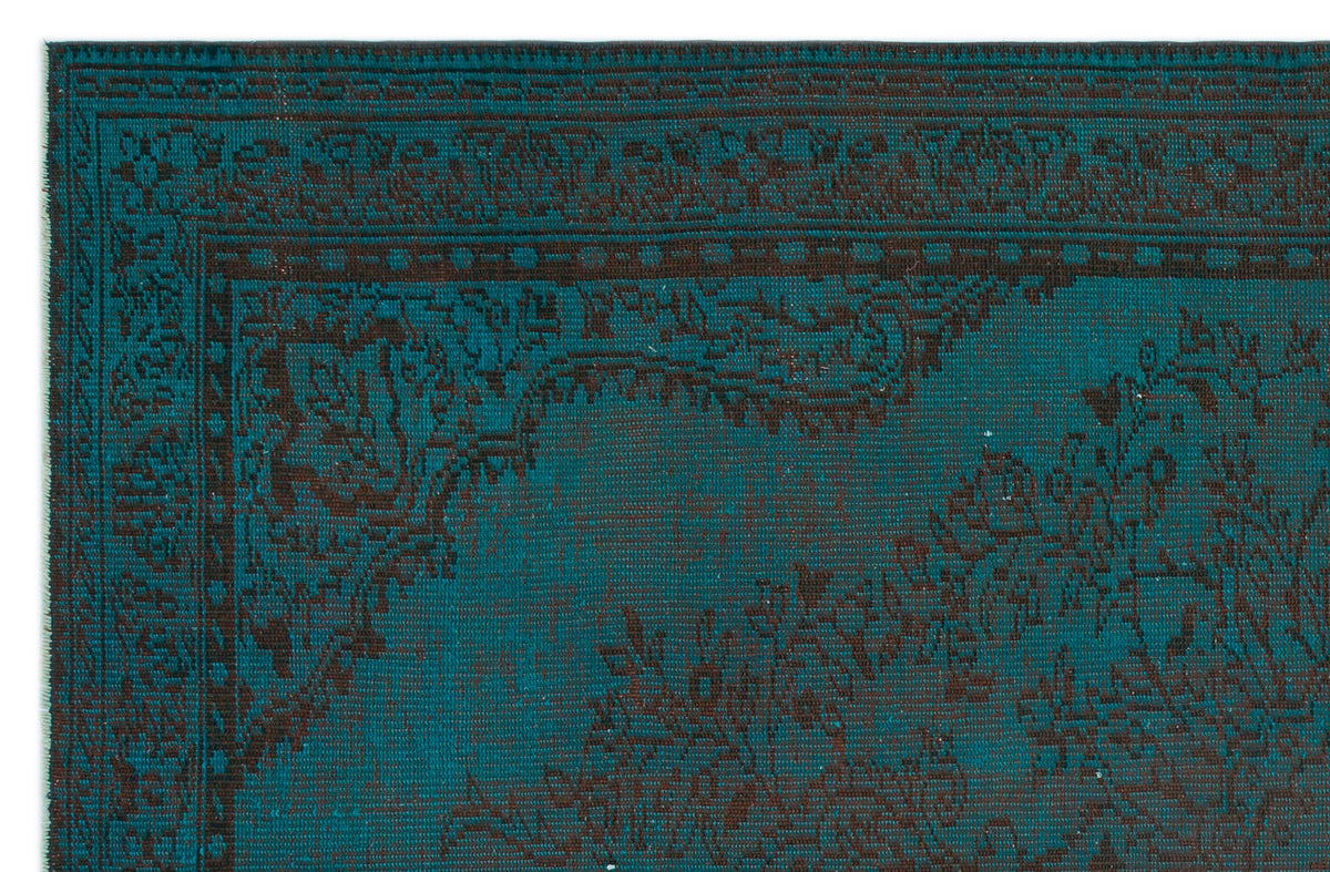 Teal and dark brown rug with a traditional ornate border and floral medallion pattern.