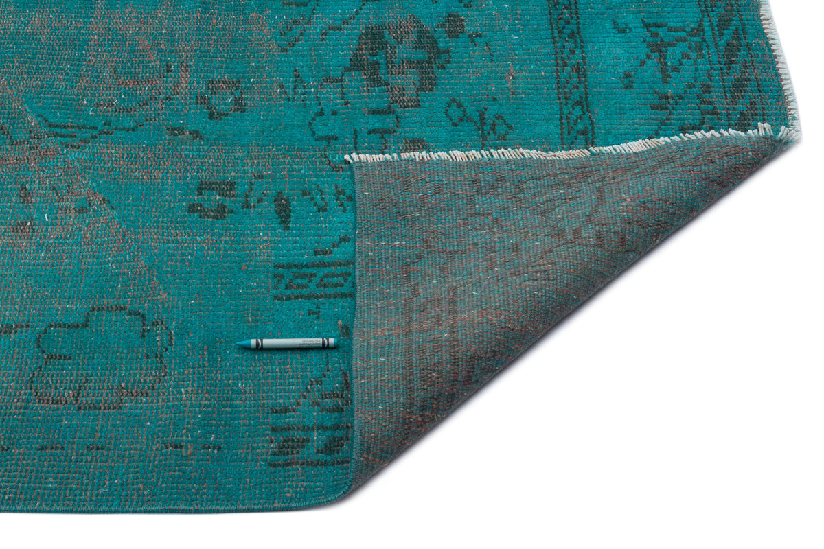 Teal and charcoal distressed vintage-style rug with a folded corner revealing the woven backing.