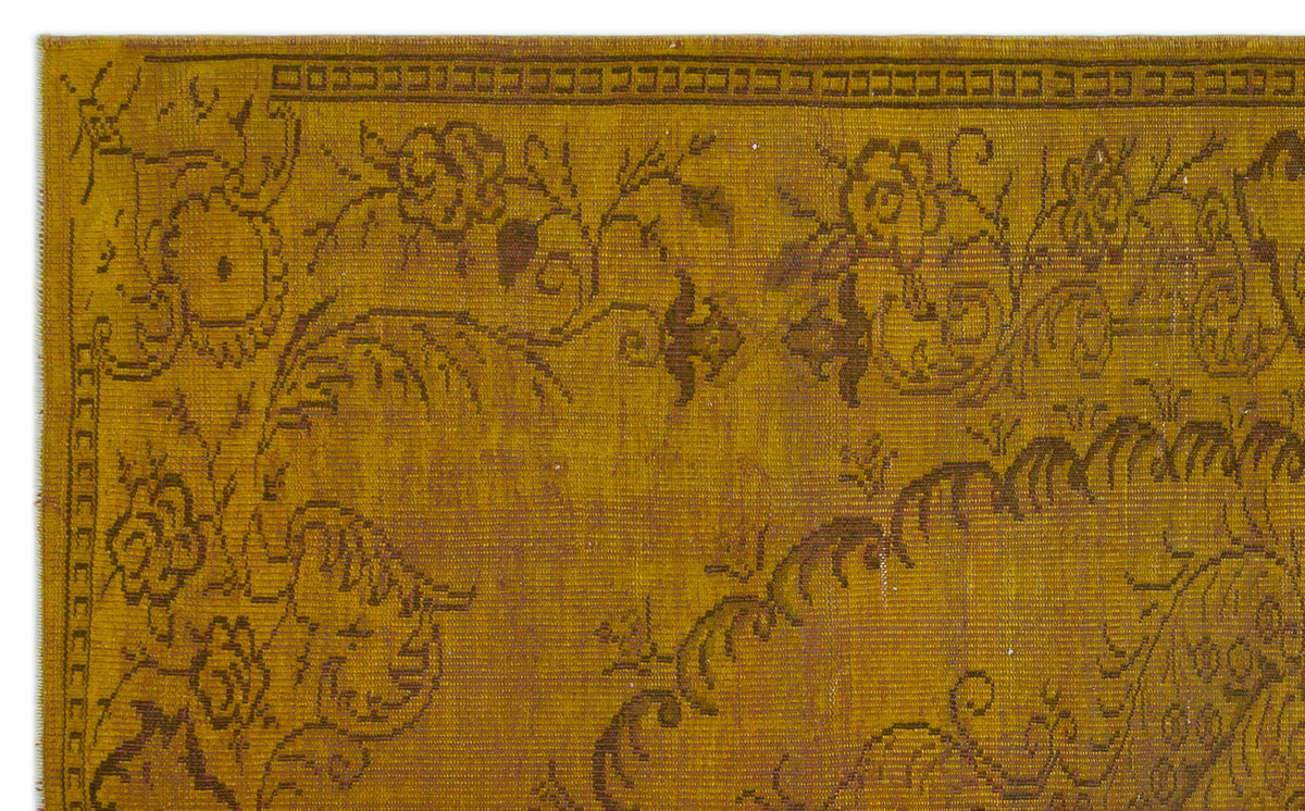 Mustard yellow rug with a dark brown floral medallion pattern and a geometric border.