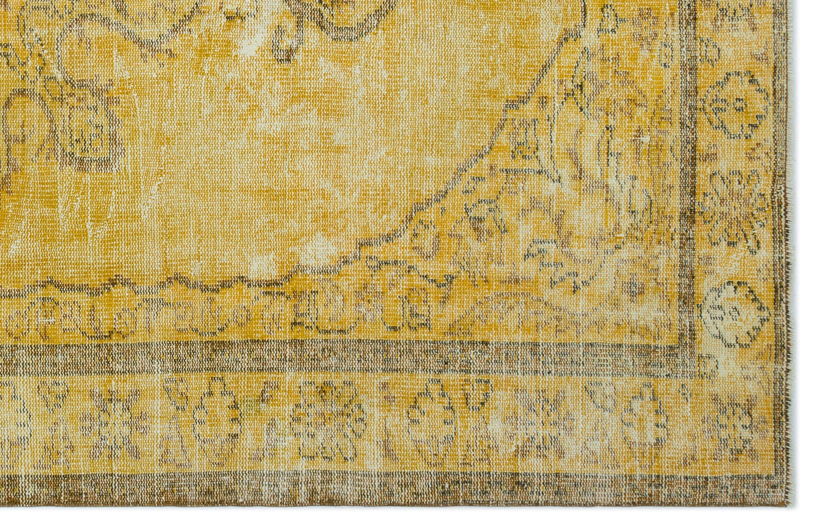 Mustard yellow and brown distressed rug with a traditional floral medallion pattern and a wide decorative border.