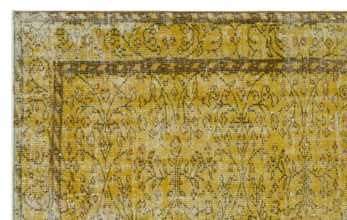 Mustard yellow and brown vintage-style rug with a distressed floral medallion pattern and a decorative border.