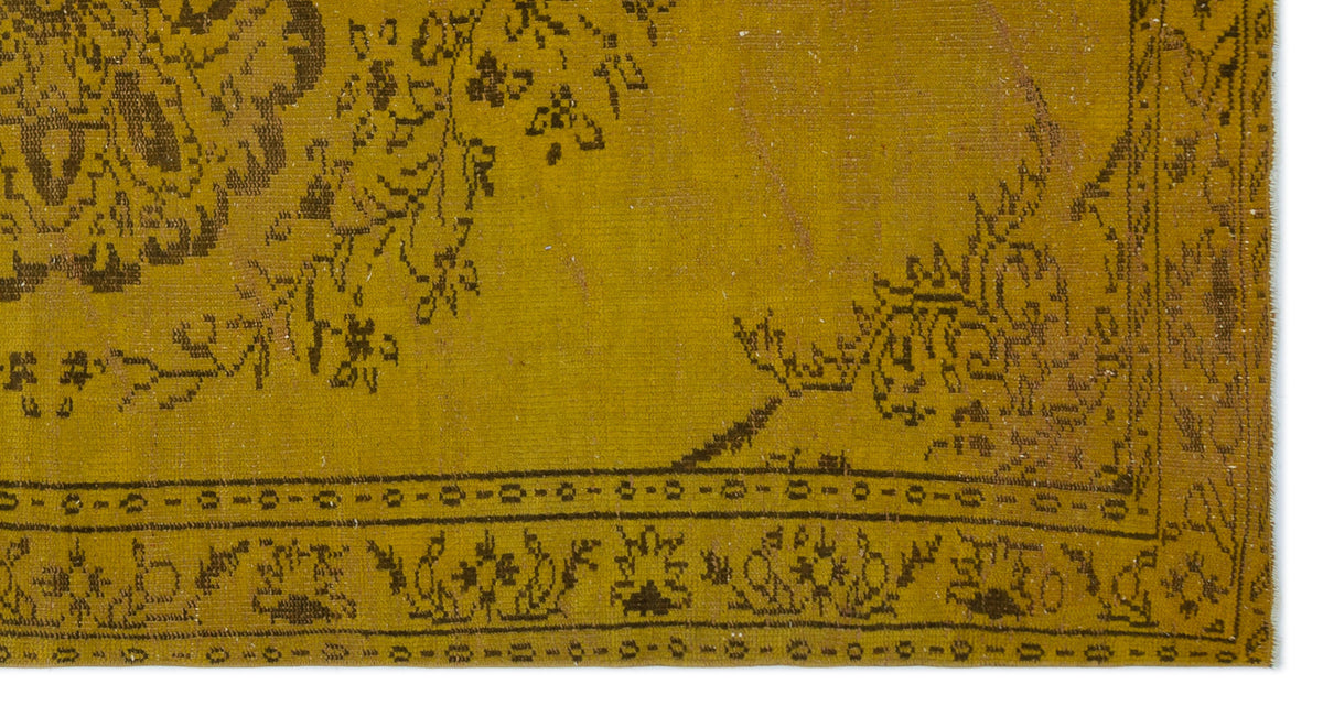 Mustard yellow rug with a dark brown distressed floral medallion pattern and a geometric border.
