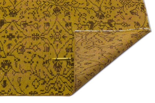 Load image 1 in gallery view. Mustard yellow rug with a distressed brown floral pattern and a folded corner showing the underside.