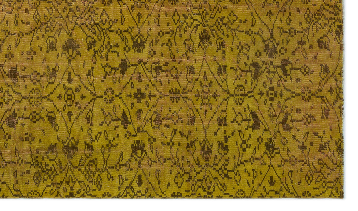 Mustard yellow rug with a dark brown distressed geometric lattice and floral medallion pattern.