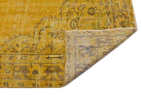 Load image 1 in gallery view. Distressed mustard yellow rug with a faded floral medallion pattern, shown folded to reveal the neutral backing.