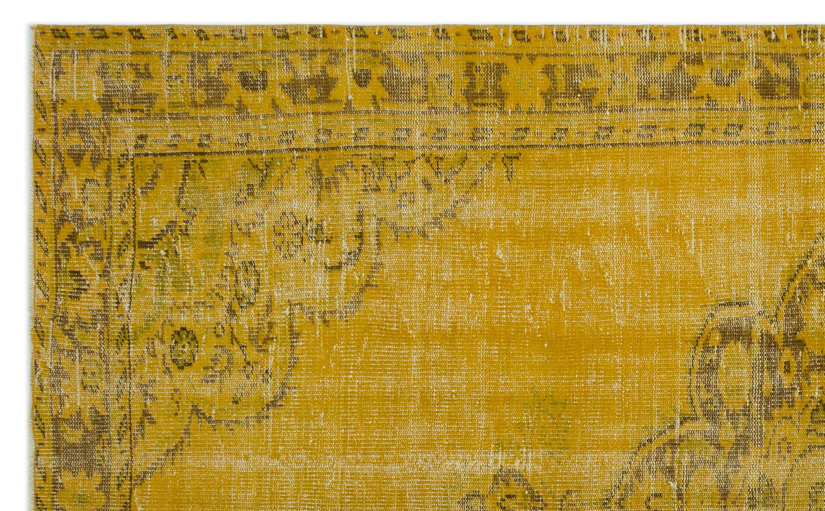 Mustard yellow vintage-style rug with a distressed, faded traditional medallion pattern in brown and olive green.