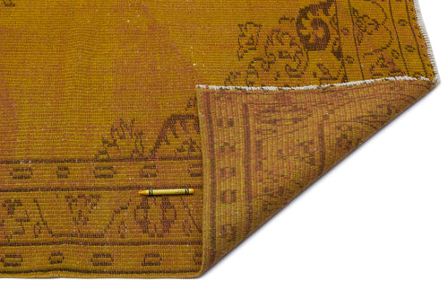 Load image 1 in gallery view. Mustard yellow vintage rug with a faded brown traditional border pattern, shown with a corner folded over.