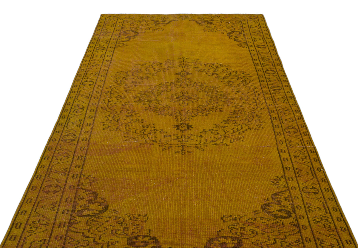 Mustard yellow vintage-style rug with a dark brown central floral medallion and geometric border on a white background.