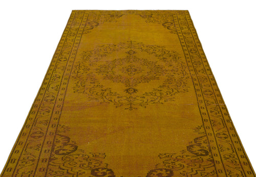 Load image 1 in gallery view. Mustard yellow vintage-style rug with a dark brown central floral medallion and geometric border on a white background.