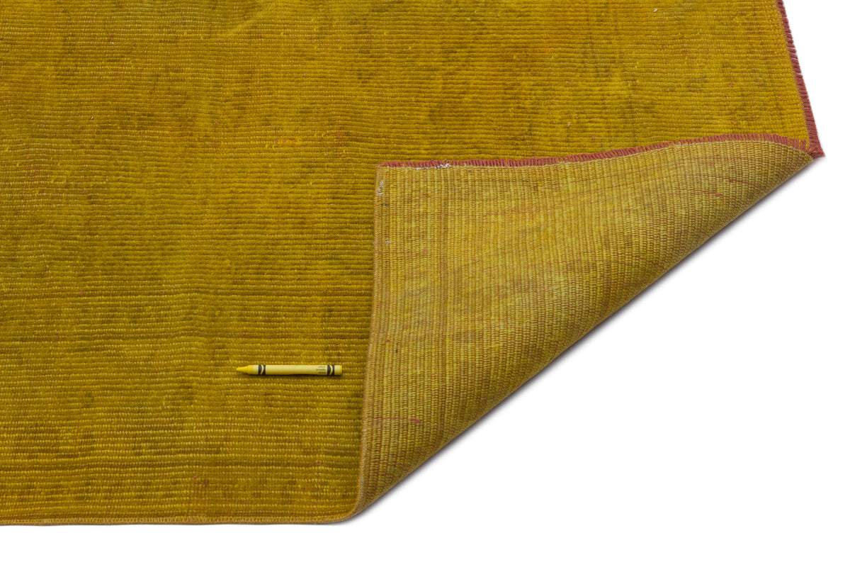 Mustard yellow ribbed rug with a folded corner revealing a lighter underside and red stitched edges.