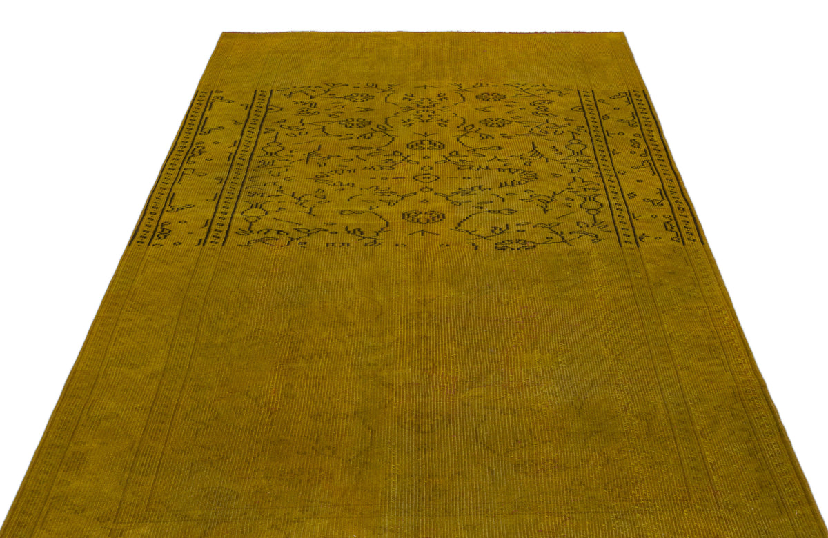 Mustard yellow vintage-style rug with a faded black floral medallion pattern and a decorative border.