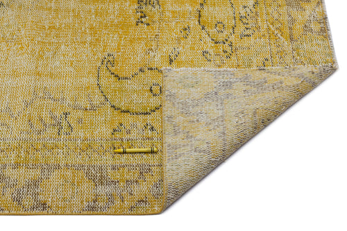 Load image 1 in gallery view. Yellow and beige distressed rug with a faded paisley pattern, shown with a corner folded over on a white background.