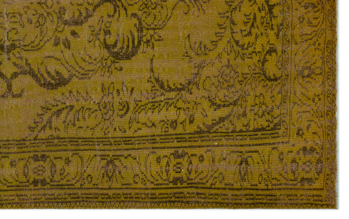 Olive green vintage-style rug with a dark brown distressed floral medallion pattern and a geometric border.