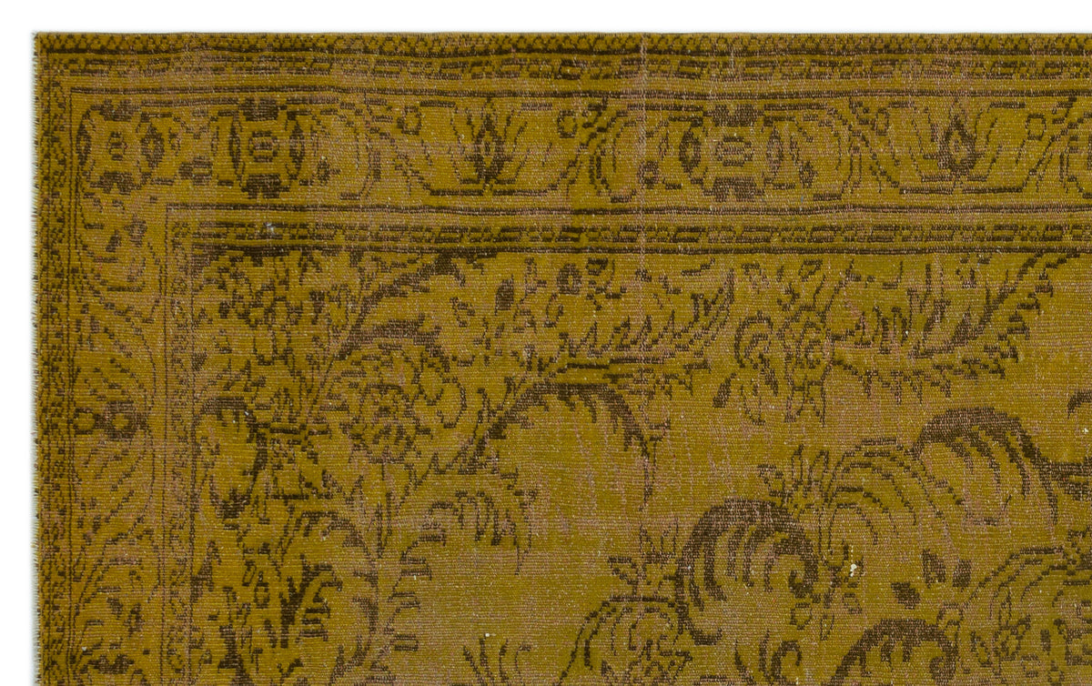 Mustard yellow and dark brown vintage-style rug with a distressed floral medallion pattern and ornate border.