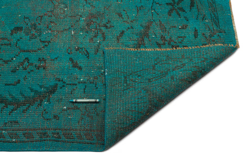 Load image 1 in gallery view. Teal rug with a distressed black floral pattern and a folded corner revealing the woven backing on a white background.
