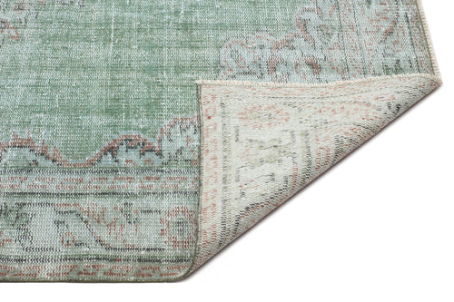 Load image 1 in gallery view. Sage green and terracotta distressed traditional rug with a folded corner revealing the woven backing.
