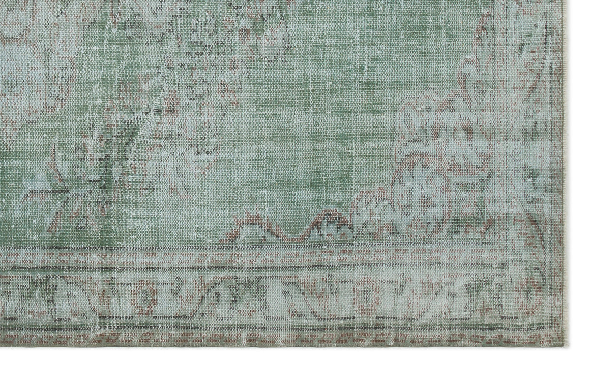 Sage green and cream distressed rug with a faded traditional medallion pattern and a bordered edge.