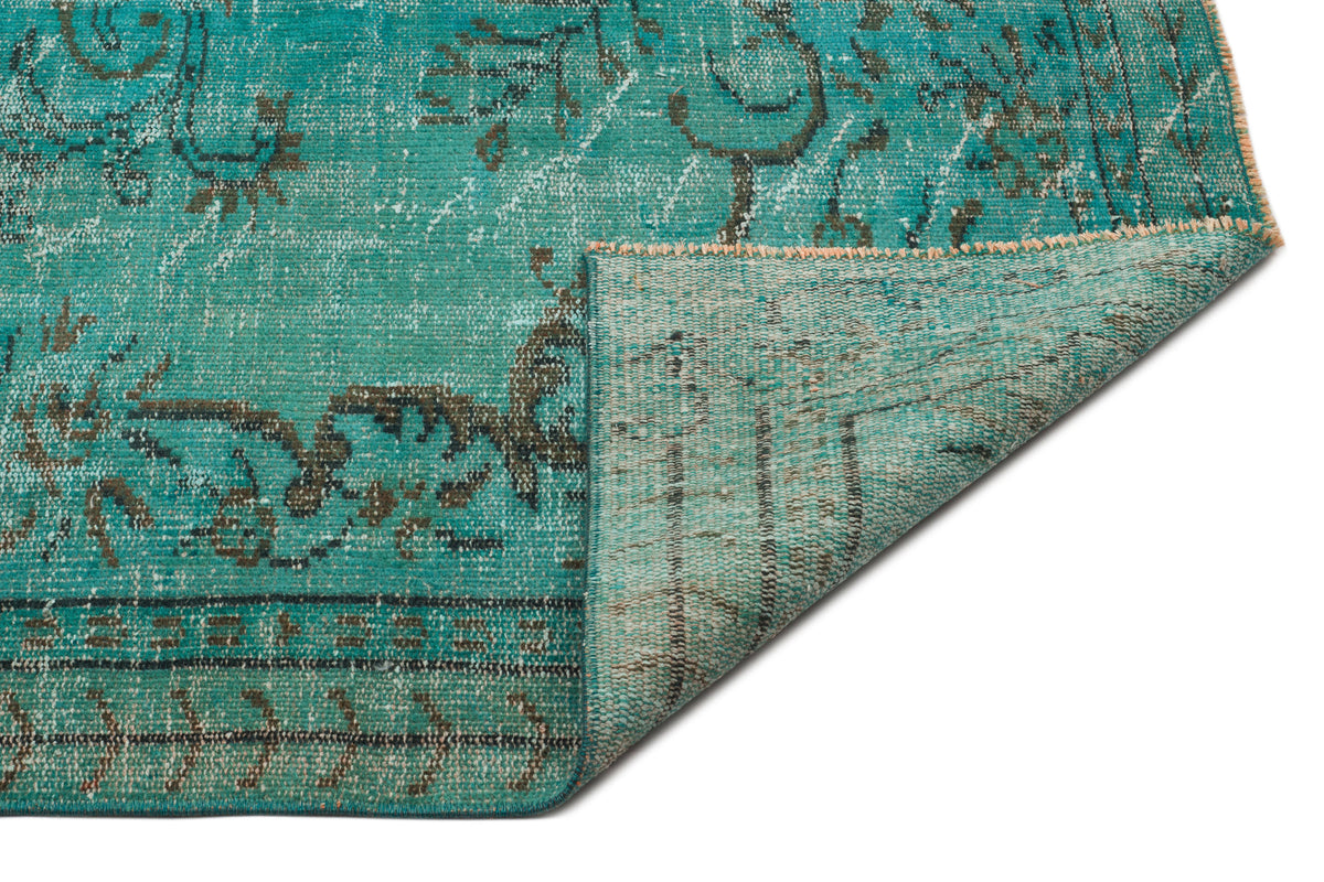 Teal and charcoal distressed traditional rug with a folded corner revealing the woven backing on a white background.