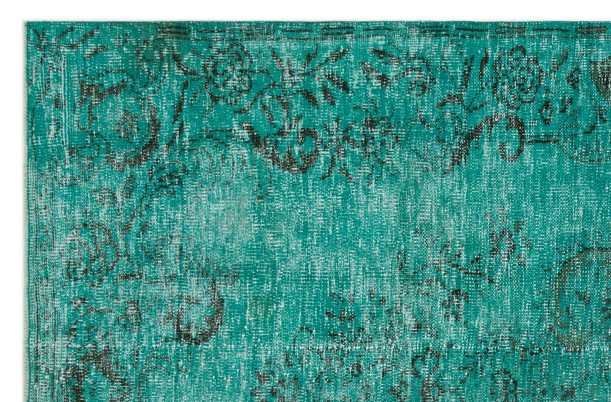 Teal and black distressed rug with a faded floral pattern and traditional border.