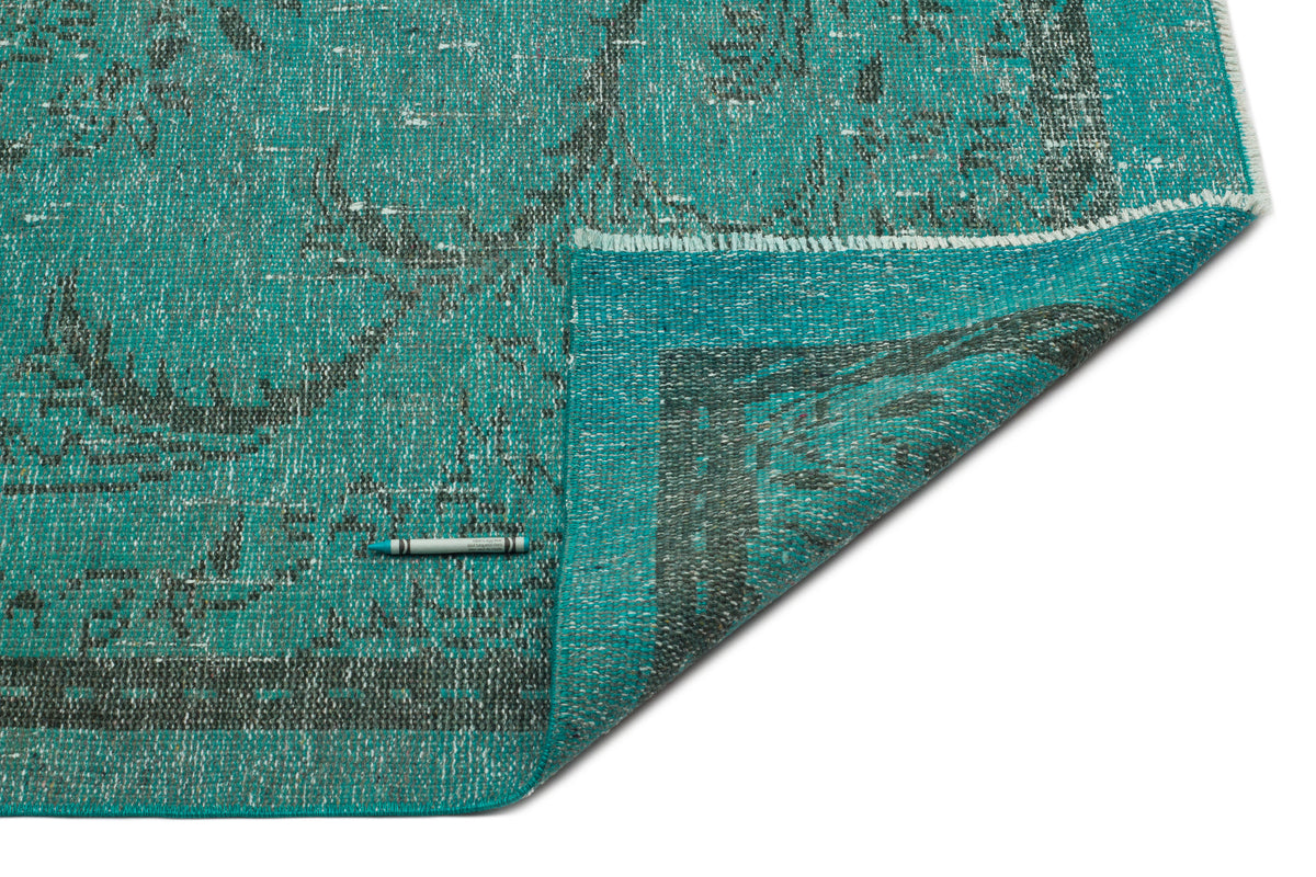 Teal and charcoal distressed medallion rug with a folded corner, shown on a white background.