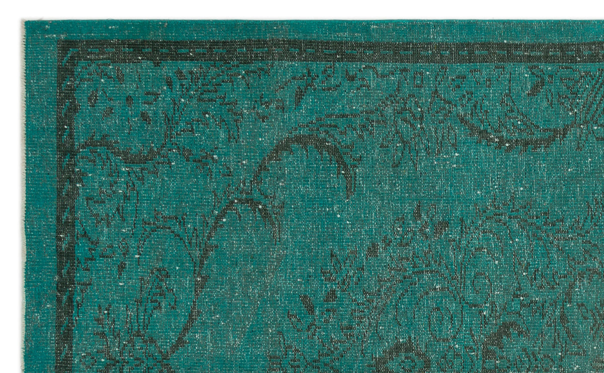 Teal rug with a distressed black floral pattern and a thin linear border.
