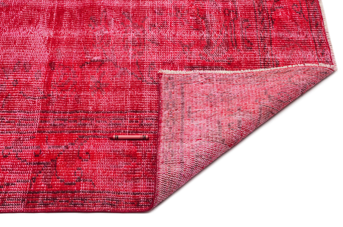 Distressed red and pink overdyed rug with a folded corner, isolated on a white background.