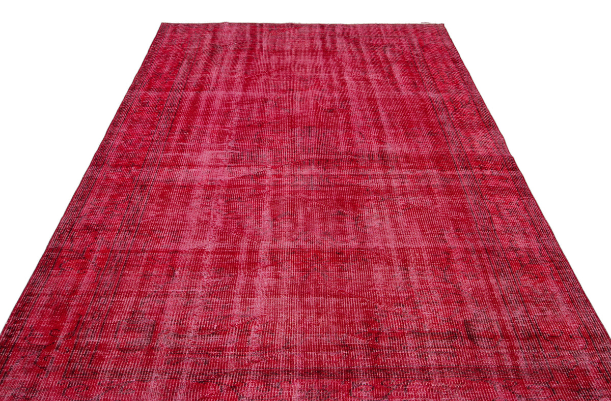 Distressed magenta and red vintage-style rug with a faded, overdyed geometric pattern on a white background.