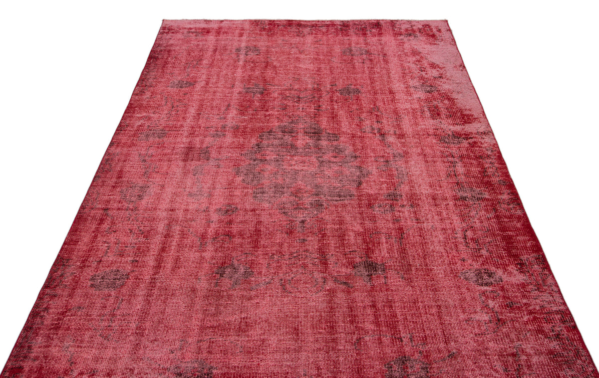 Distressed red vintage-style rug with a faded central medallion and dark grey ornamental patterns.