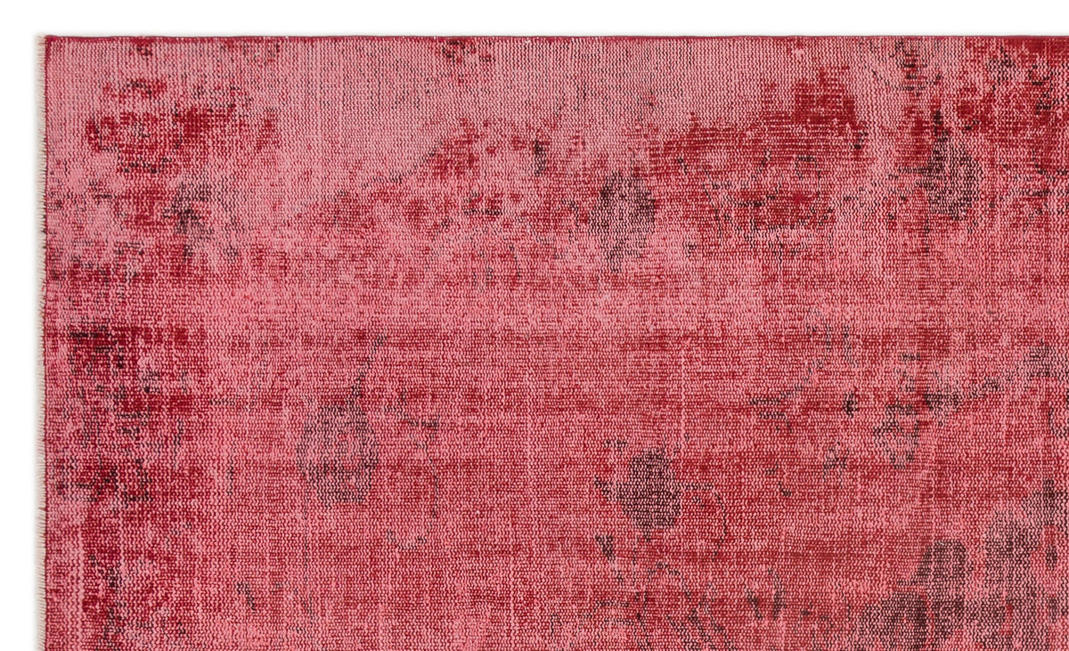 Red and pink distressed rug with a faded, abstract vintage-style pattern.