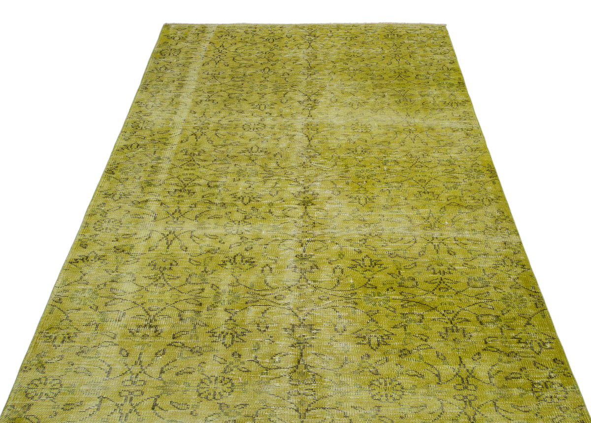Chartreuse distressed area rug with a faded black floral vine pattern on a white background.