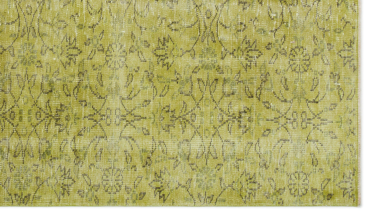Chartreuse distressed rug with a faded, dark grey floral medallion pattern.