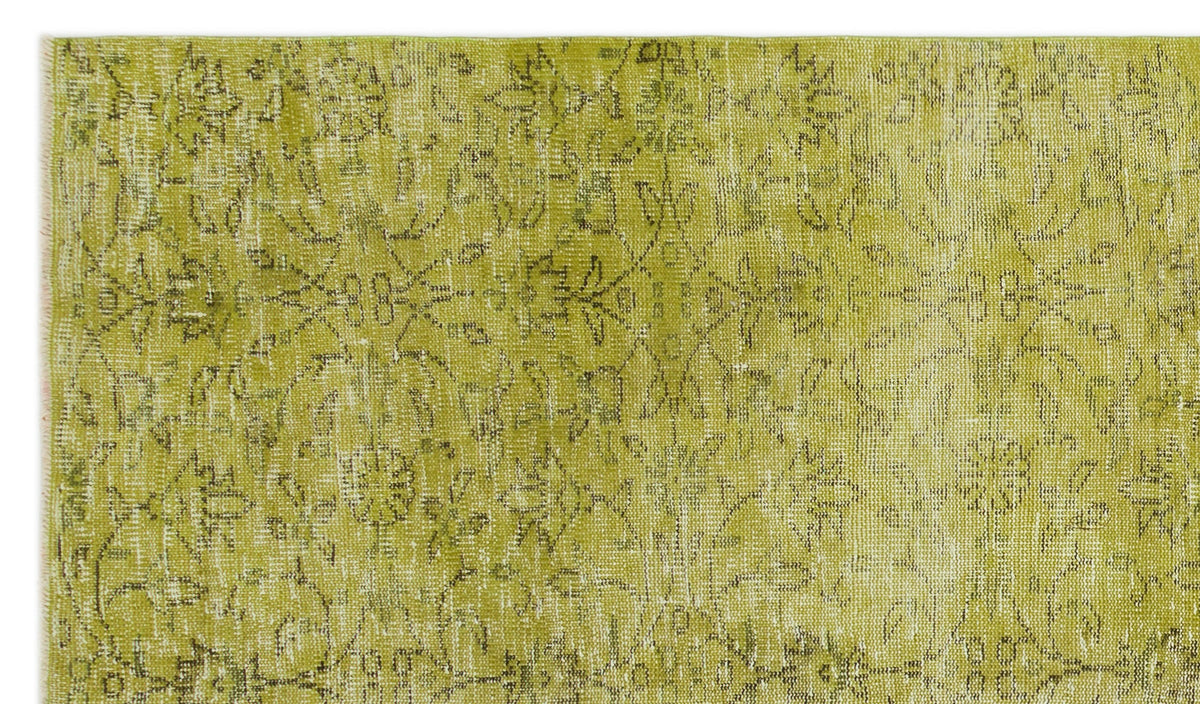 Chartreuse and white distressed rug with a faded traditional floral medallion pattern.