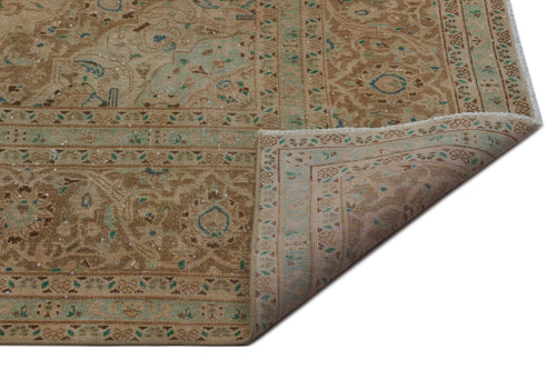 Load image 1 in gallery view. Tan and teal traditional Persian-style rug with a distressed floral medallion pattern and a folded corner.