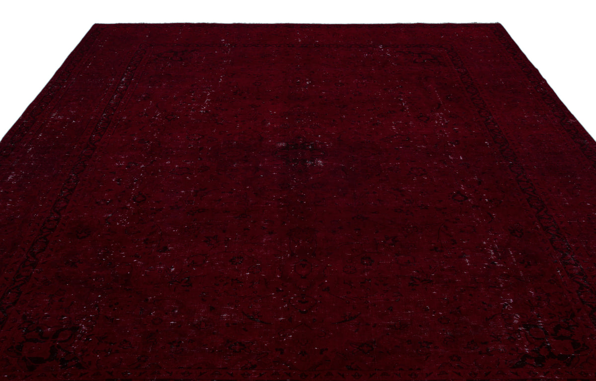 Deep burgundy traditional rug with a distressed, faded black floral medallion pattern on a white background.
