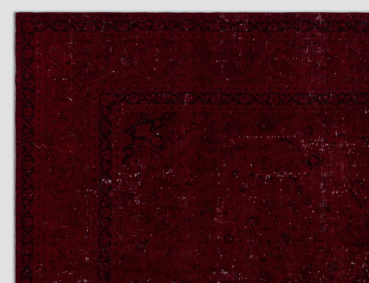 Deep red distressed rug with a dark, intricate traditional border and faded floral motifs.
