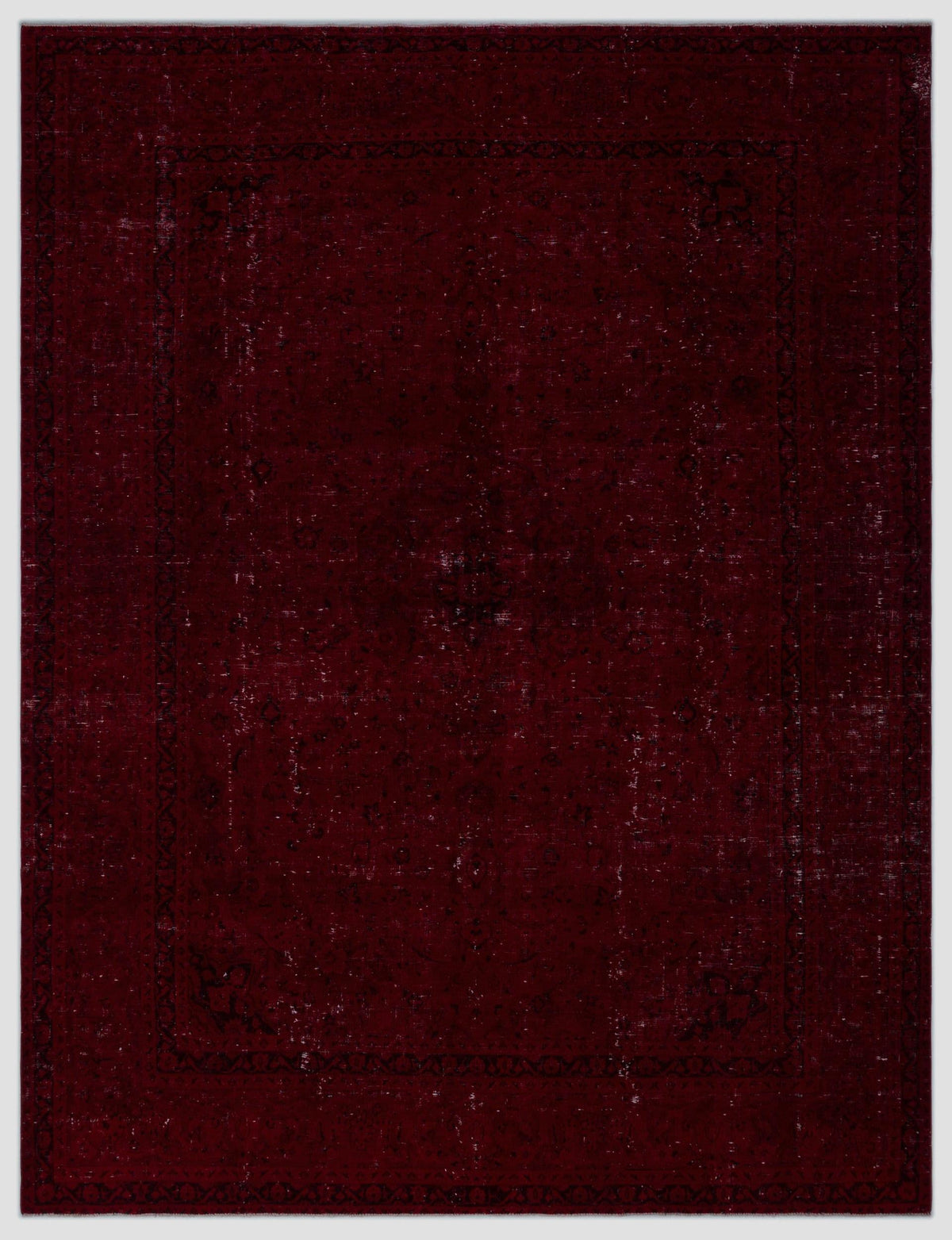Deep burgundy distressed rug with a faint, traditional black floral medallion pattern and a decorative border.