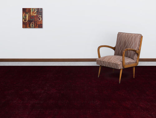 Load image 1 in gallery view. Solid deep burgundy rug with a subtle distressed texture, styled in a room with a patterned armchair and wall clock.