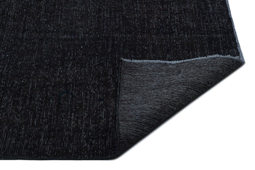 Load image 1 in gallery view. Solid black rug with a subtle white speckled texture and a folded corner revealing a dark grey woven backing.