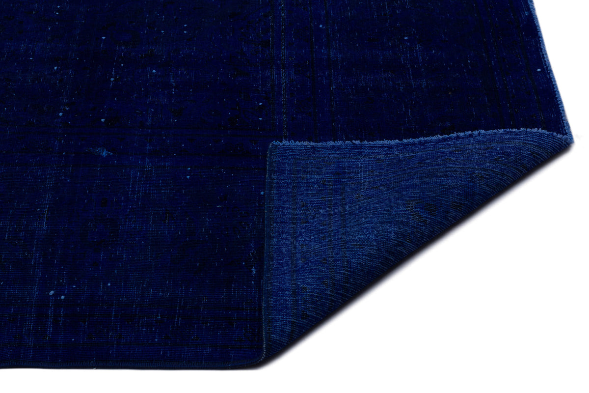 Deep navy blue rug with a subtle distressed texture and a folded corner revealing the underside.