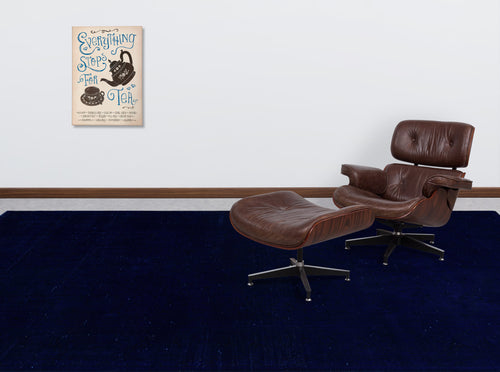Load image 1 in gallery view. Solid navy blue rug in a room with a brown leather lounge chair and tea-themed wall art.