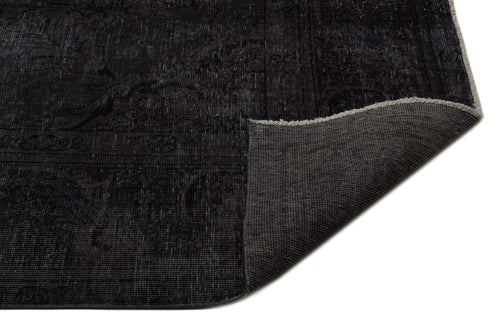 Load image 1 in gallery view. Charcoal black distressed rug with a faint traditional medallion pattern and a corner folded to show the woven backing.